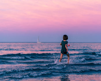 Boy on beach against sky during sunset