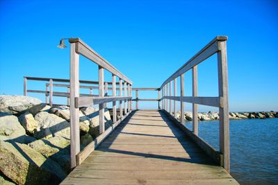Bridge over calm blue sea against clear sky