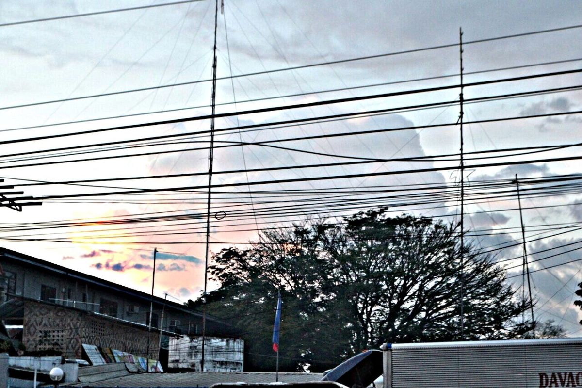 architecture, built structure, building exterior, sky, low angle view, city, glass - material, power line, modern, building, cloud - sky, cable, electricity pylon, office building, tree, day, transparent, cloud, no people, city life