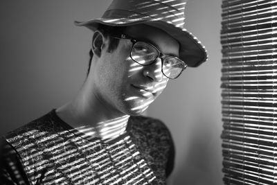 Close-up of man wearing hat and eyeglasses by window at home