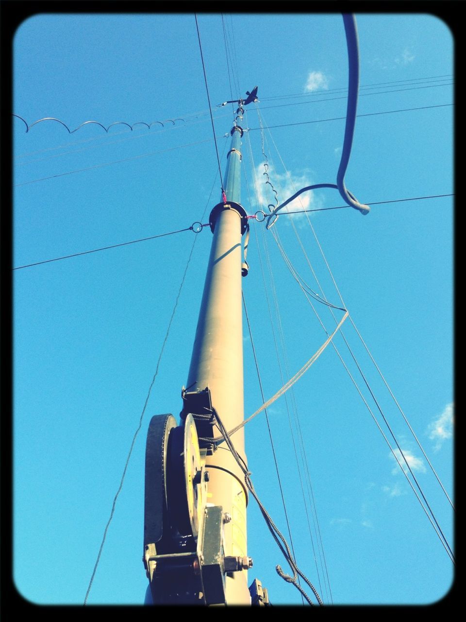 low angle view, fuel and power generation, transfer print, power supply, electricity, blue, power line, technology, clear sky, auto post production filter, electricity pylon, transportation, connection, cable, sky, mast, mode of transport, crane - construction machinery, day, outdoors