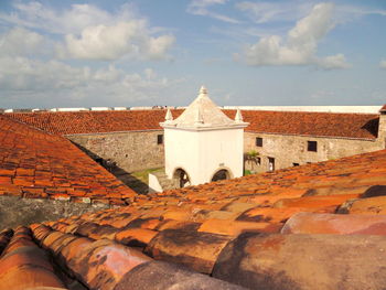 View of a building in the centre of a fortress surrounded by brown tiles against sky