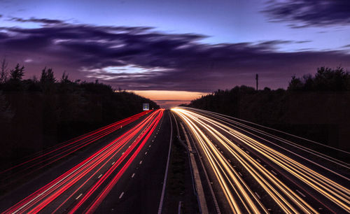 High angle view of light trails on multiple lane highway at sunset