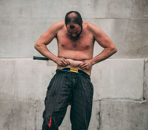 Full length of shirtless man standing against wall