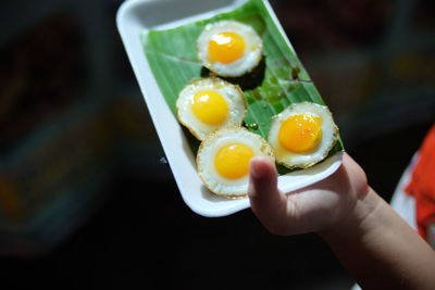 Close-up of chid's hand holding fried eggs