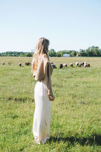 Rear view of woman standing on field against clear sky