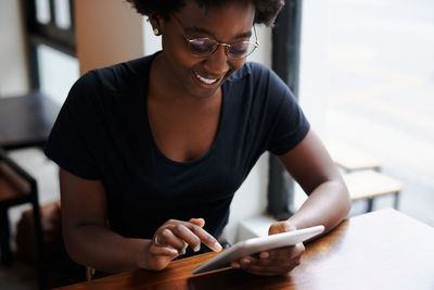 Midsection of man using mobile phone while sitting on table