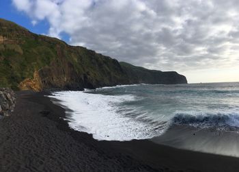 Blue wave breaking in the black sand beach