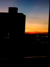 Silhouette buildings against sky at sunset