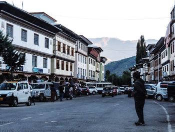 People on street amidst buildings in city against sky