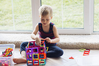 The child is playing with a multi-colored magnetic constructor, building a tower. educational toys