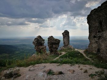 Rock formations on landscape against cloudy sky