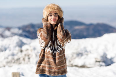 Portrait of woman standing against mountains during winter