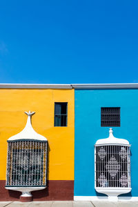 Blue and yellow houses against clear sky on sunny day