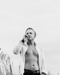 Full length of shirtless man standing against sky