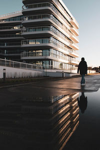 Rear view of man standing on street against buildings in city