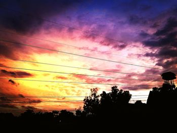 Silhouette trees against dramatic sky during sunset