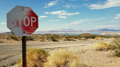 Road sign on landscape against sky