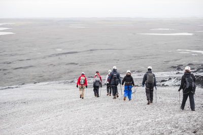 Rear view of people walking on snow covered land