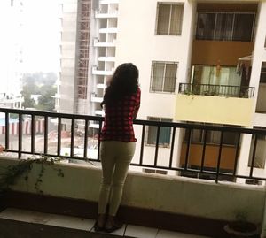 Rear view of woman standing by railing against building