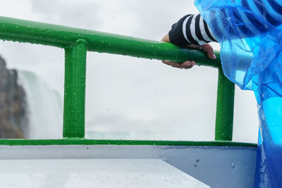 Low section of man holding water against sky