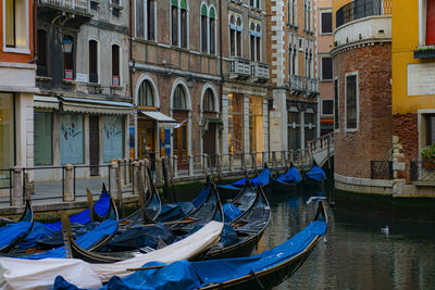 Boats moored in canal by buildings in city