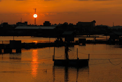 Silhouette buildings against orange sky during sunset