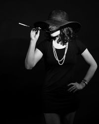 Young woman wearing hat standing against black background