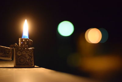 Lit cigarette lighter on table at night