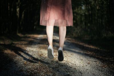 Low section of woman walking in forest