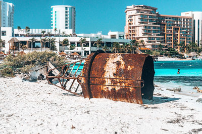 Wreckage of nautical buoy on beach with luxury hotels in background