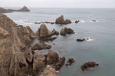 Scenic view of rocks in sea against sky