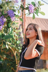 Portrait of young woman standing against plants