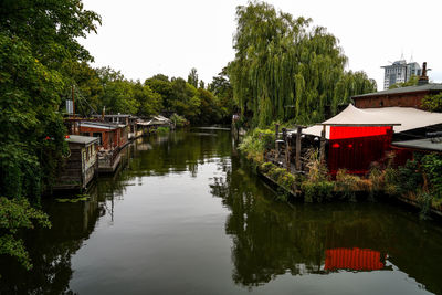 Canal amidst trees and buildings against sky