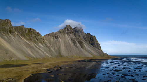 Scenic view of mountain by sea against sky