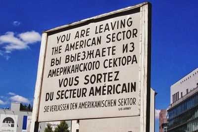 Low angle view of sign board against blue sky