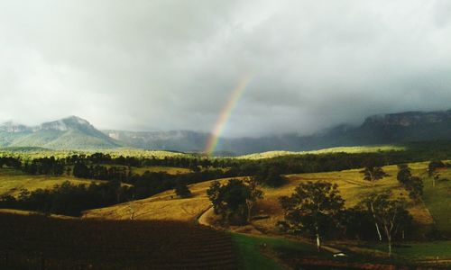 Scenic view of rainbow over landscape against sky