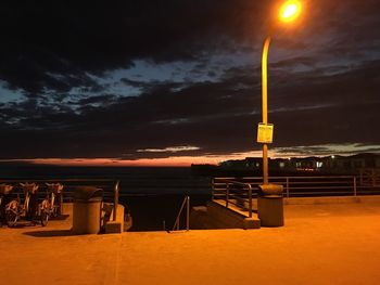 Scenic view of illuminated beach against dramatic sky