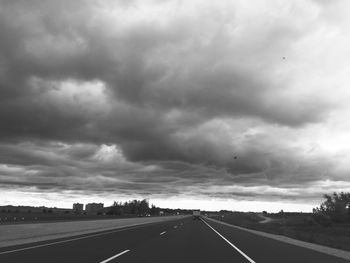 Empty country road against cloudy sky