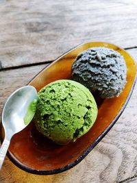 Green tea matcha ice cream 2 scoops in bowl on a wooden table background. top view. close up.