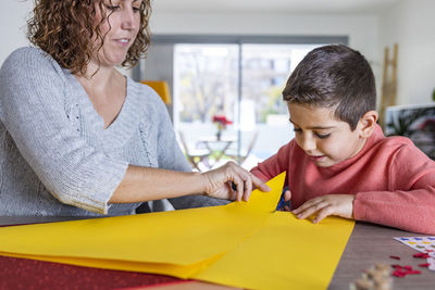 Mother and son making crafts at home with cardstocks and stickers