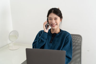 Young woman using laptop while sitting on table