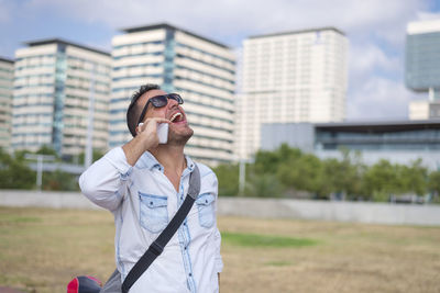 Cheerful man talking over smart phone while standing on land