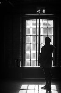 Rear view of silhouette woman standing against window