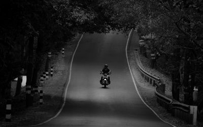 Full length of man riding motorcycle on road