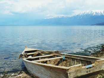 Rowing boat on shore against snowcapped mountain