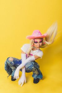 High angle view of woman wearing hat standing against yellow background