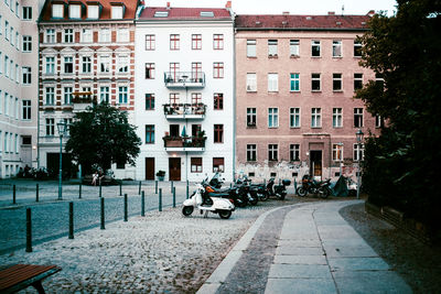 Scooter and motorcycles parked on road against buildings