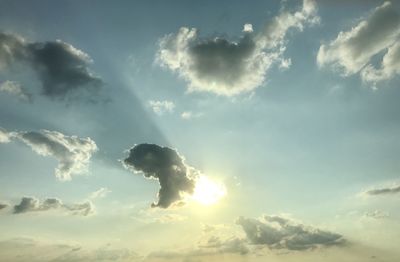 Low angle view of sunlight streaming through clouds