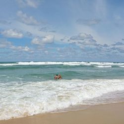 Scenic view of beach against cloudy sky